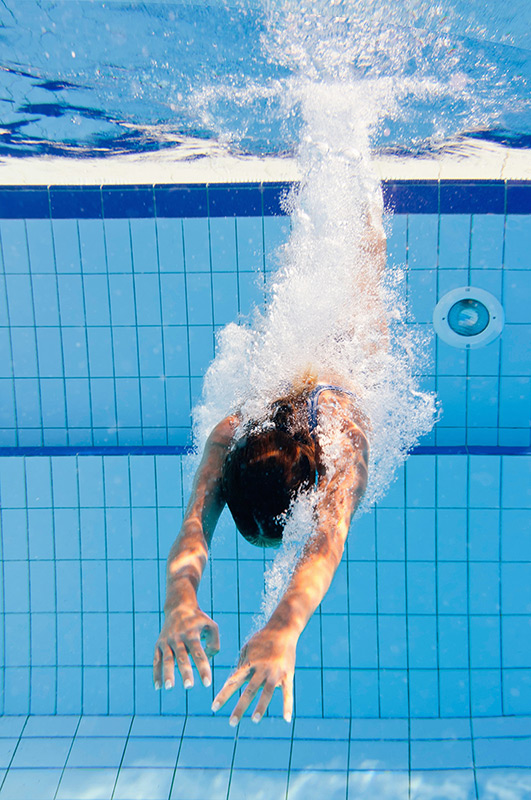 Diving-into-a-nice-clean-pool Underwater view of woman diving into pool surrounded by bubbles